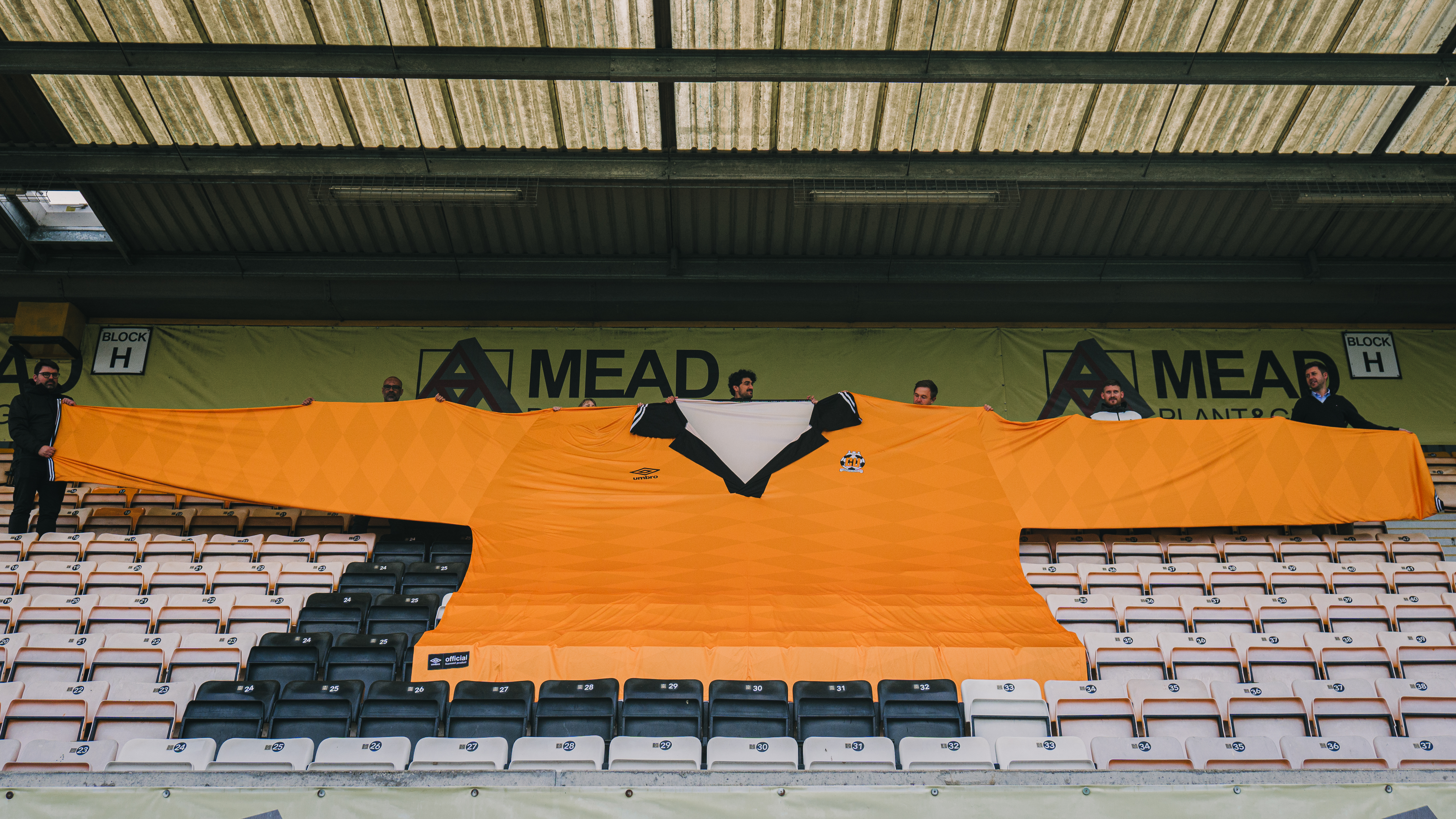 Cambridge United staff hold out a giant replica shirt