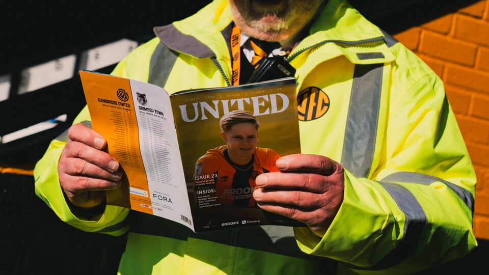 A steward reading the Matchday Programme